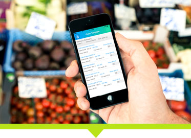 Sales rep holding a phone infront of some diferent produce, using a sales rep software to create an invoice using a digital invoice template